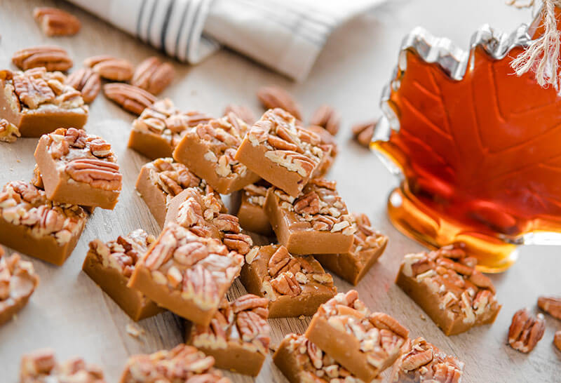 Delicious maple fudge with pecan and maple syrop on the background