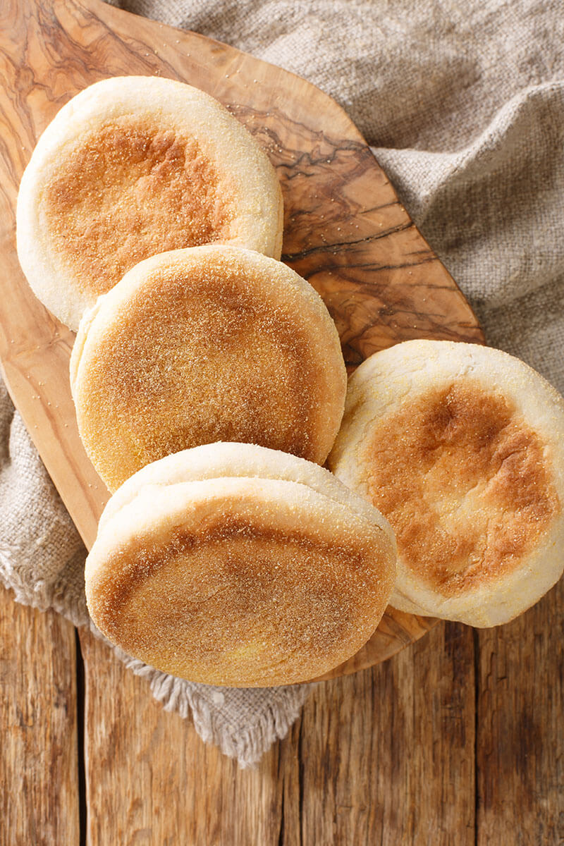 Homemade English muffins buns close-up in a board on the table.