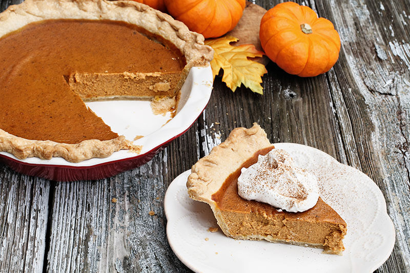 Slice of homemade pumpkin pie over a rustic wooden background. Extreme shallow depth of field with selective focus.