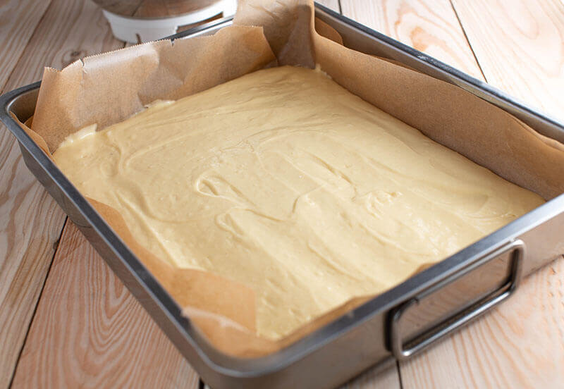 Fresh and homemade sponge cake base served in a square baking pan on wooden table background