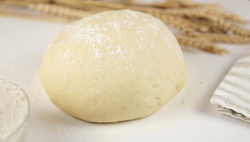 Raw dough, flour and ears of wheat on white background, close-up front view. Home baking concept