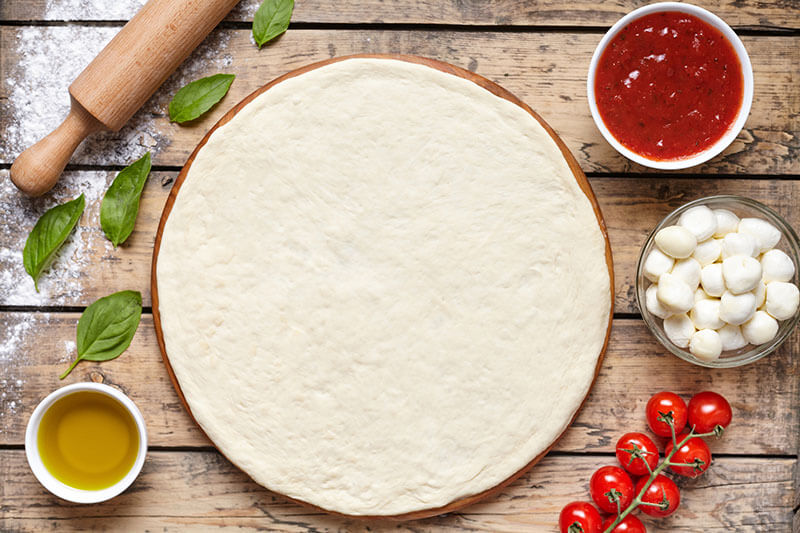 Raw dough preparation or pizza with ingredient: tomato sauce,