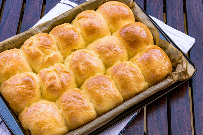 Fresh and homemade dinner rolls / buns in a baking sheet close-up image.