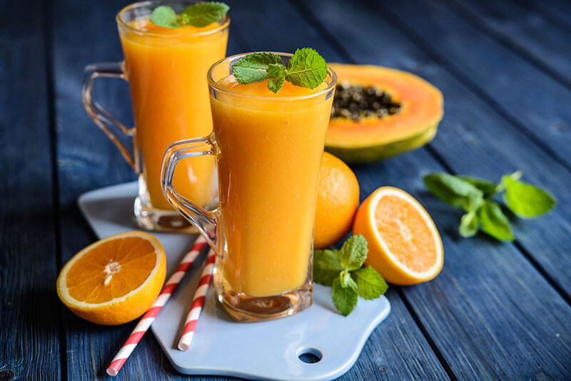 Healthy papaya, orange and mango smoothie in a glass jar